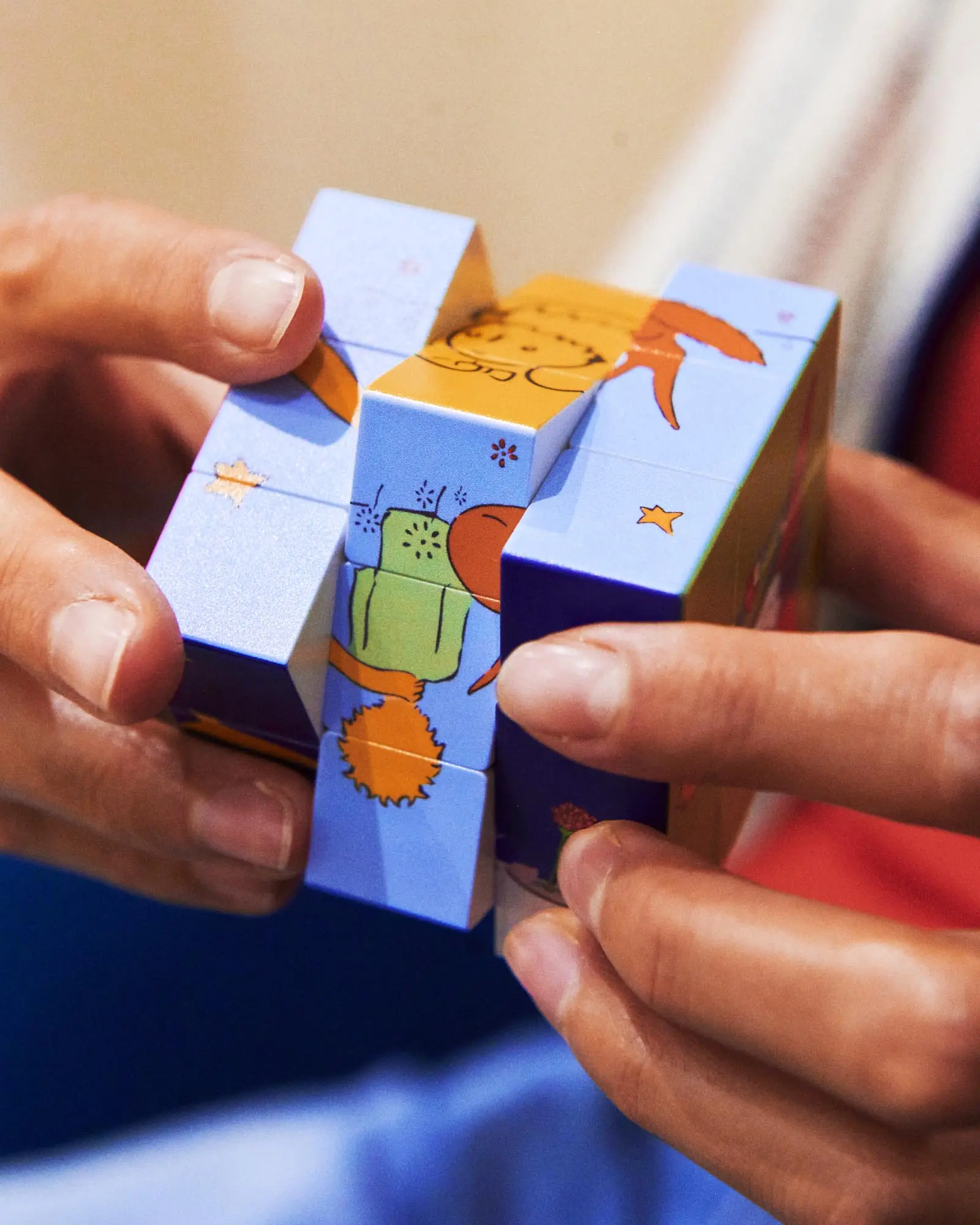 Hands turning an illustrated Little Prince cube